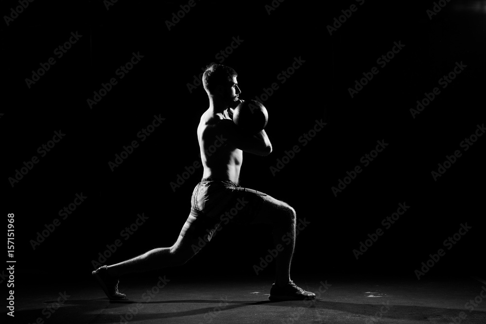 Fitness training. Man doing exercises with weights in dark gym.