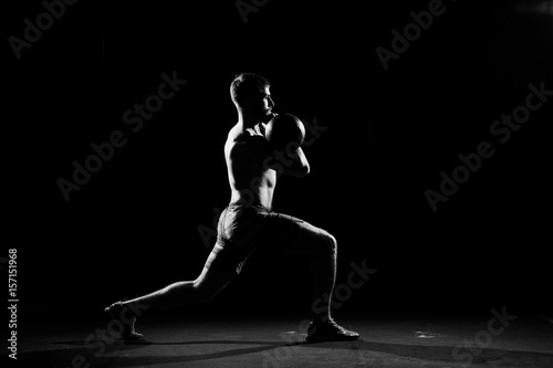 Fitness training. Man doing exercises with weights in dark gym.