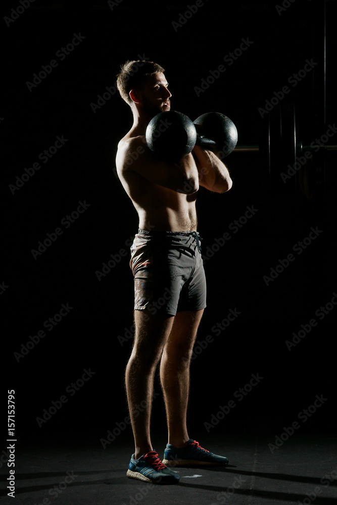 Fitness training. Man doing exercises with weights in dark gym. Fitness training. Man doing exercises with weights in dark gym.