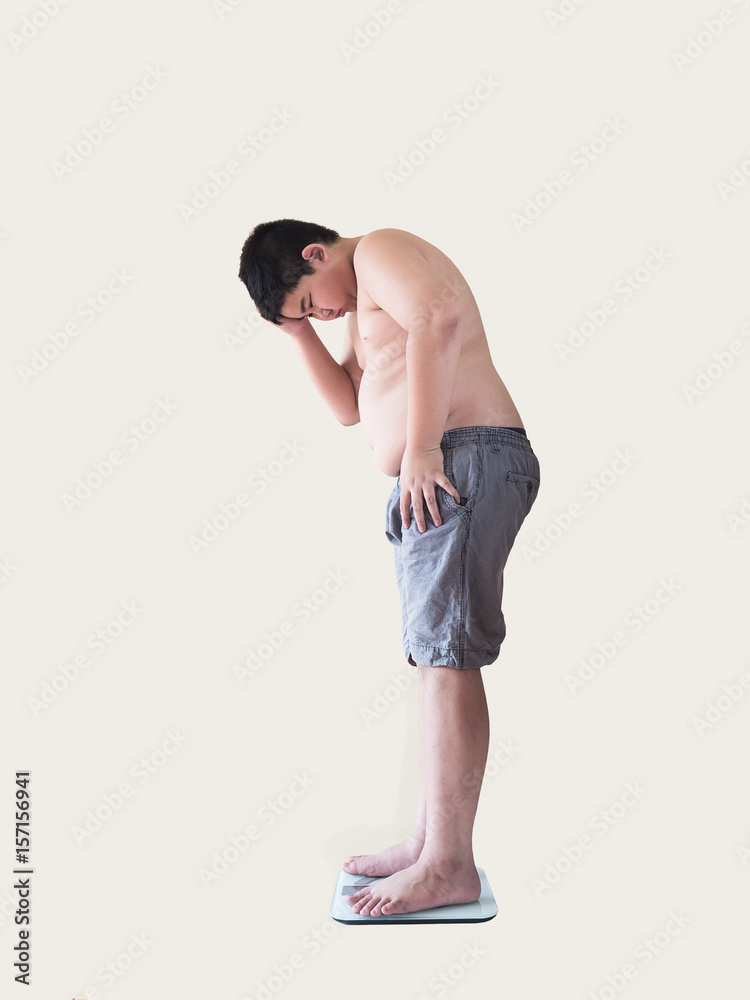 Naklejka premium Soft focus of fat boy disappoint his fatness while standing on on weighing machine over white background