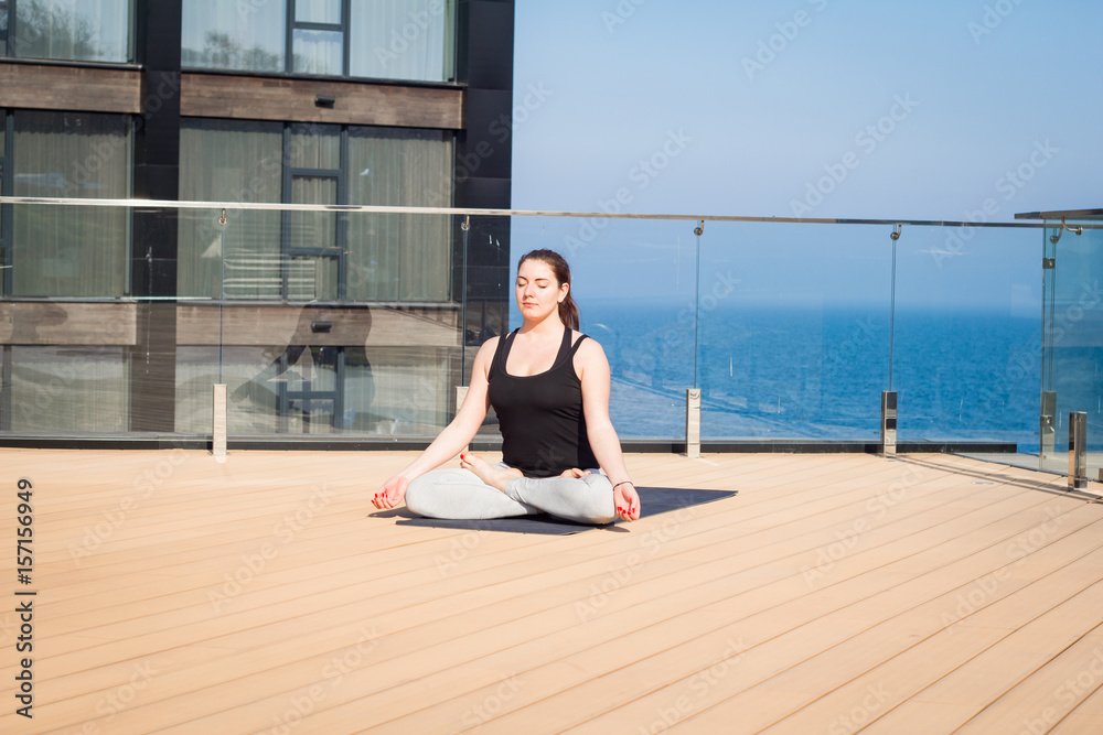 sport woman doing stretching yoga exercise on hotel roof with wooden floor stand on yoga mat