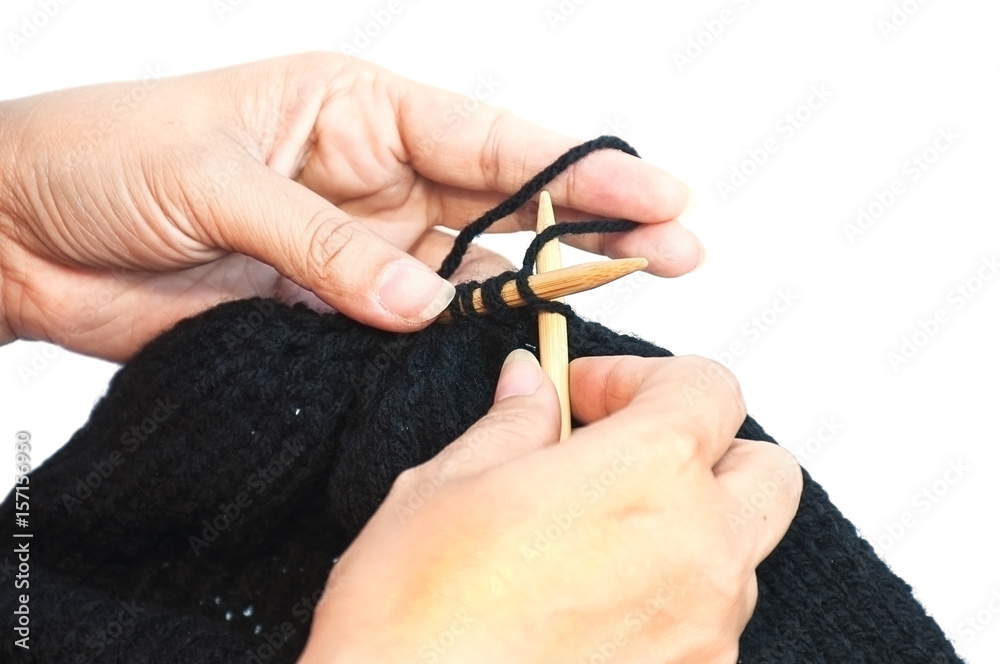 Woman's hands is making black hat knitting isolated over white background Woman's hands is making black hat knitting isolated over white background