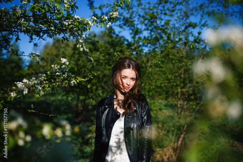 outdoor portrait of a beautiful brunette woman in white dress among blossom apple trees