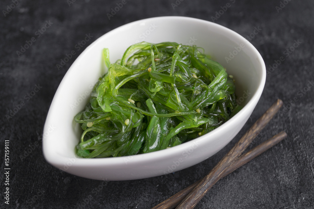 The seaweed salad in ceramic bowl with Japanese chopsticks.