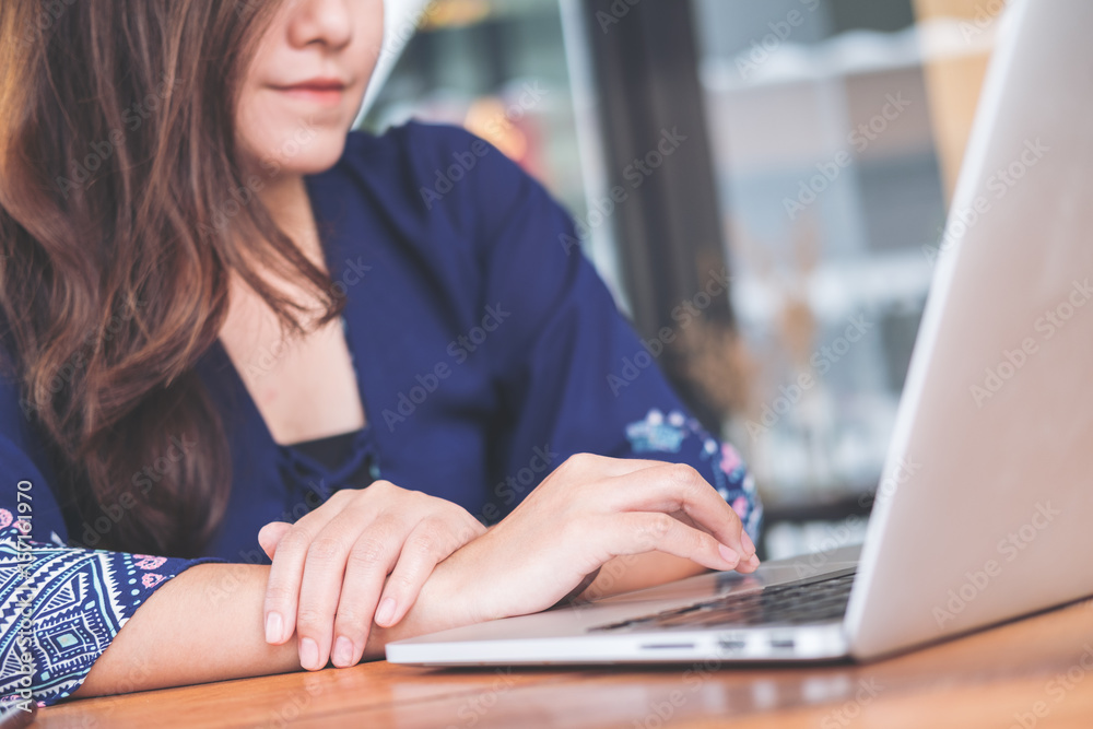 Fototapeta premium Closeup image of an Asian business woman working and typing on laptop keyboard in office
