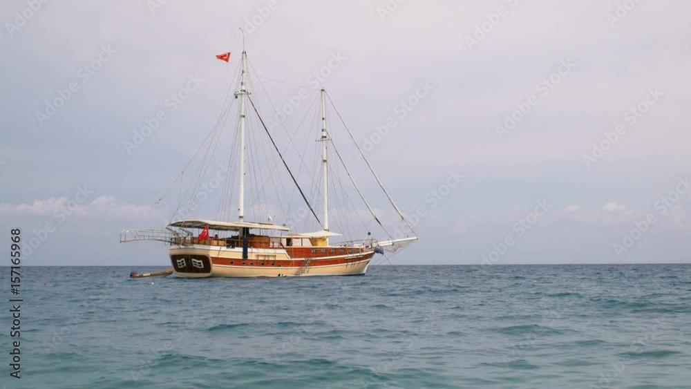 mooring touristic gulet with Turkish flags and lowered sails, near Mediterranean coastline mooring touristic gulet with Turkish flags and lowered sails, near Mediterranean coastline
