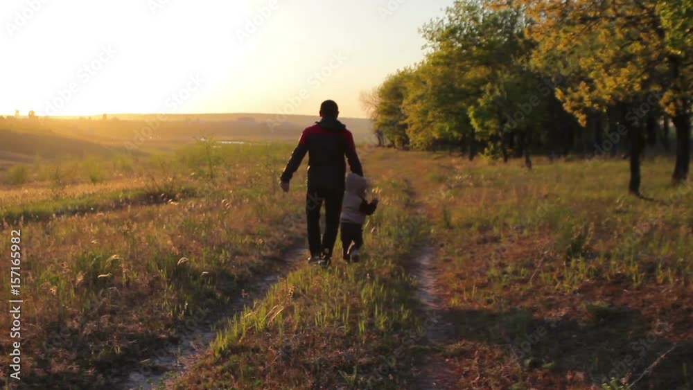 Happy dad and kid running around the forest road at sunset in the summer Happy dad and kid running around the forest road at sunset in the summer