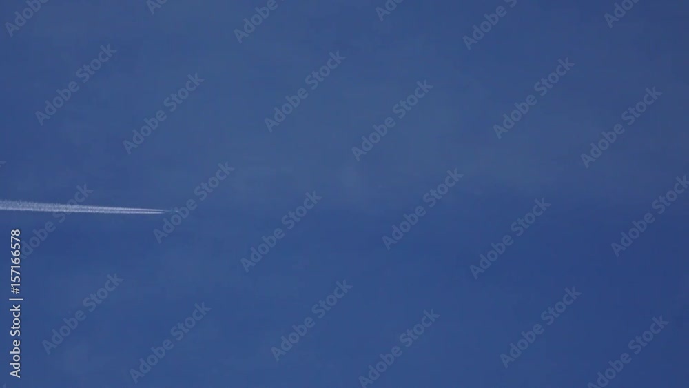 Flying commercial airplane leaving contrain in blue sky. 4K telephoto lens video Flying commercial airplane leaving contrain in blue sky. 4K telephoto lens video