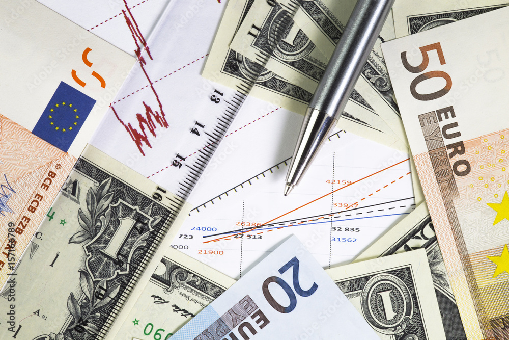 Concept of world stock market trading. Chart with prices.one us dollar bills and euro fifty and twenty bills on the graph. . Ball pen, ruler on the diagram. Macro image. Concept of world stock market trading. Chart with prices.one us dollar bills and euro fifty and twenty bills on the graph. . Ball pen, ruler on the diagram. Macro image.