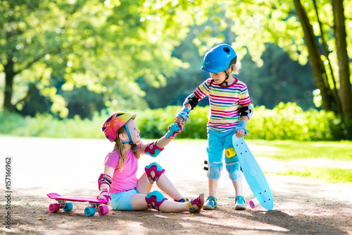 Children riding skateboard in summer park photo