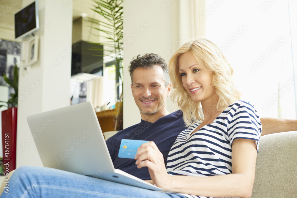 Buying online. Shot of a happy mature couple buying online with their credit card at home. Buying online. Shot of a happy mature couple buying online with their credit card at home.