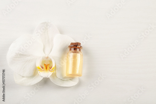 Orchid flower and oil bottle on light background