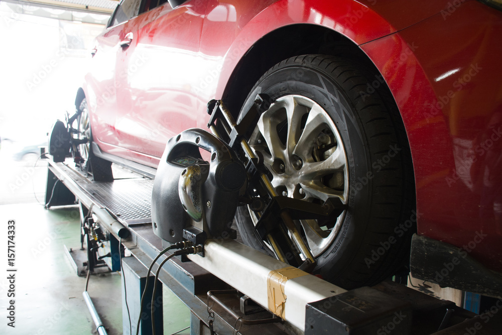 Car mechanic installing sensor during suspension adjustment. Wheel alignment work after change new tire at service station Car mechanic installing sensor during suspension adjustment. Wheel alignment work after change new tire at service station