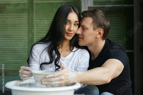 Romantic caucasian couple sculpring clay at pottr wheel. Making pottery together. photo