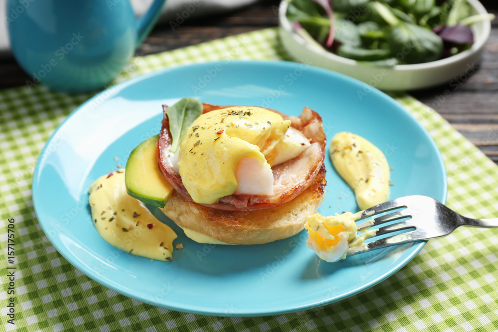 Egg Benedict with fork on plate, closeup Egg Benedict with fork on plate, closeup