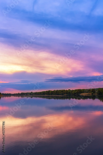 Vivid scenery of sunset at the river, colorful, dramatic evening sky reflected in the water, hdr image. Khmelnytskyi, Ukraine