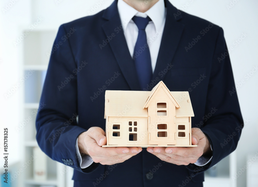 Man holding house model on blurred background Man holding house model on blurred background