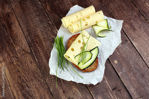 Bread with slices of cheese for lunch table. Sharing antipasti on party or summer picnic time over wooden rustic background.