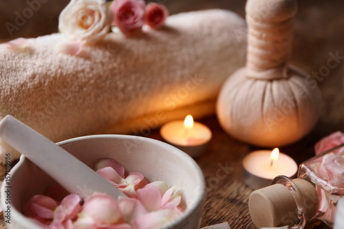 Beautiful spa composition with rose petals in bowl on wooden table