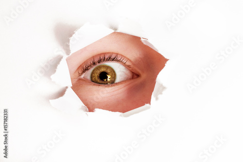 Spy eye  looking through paper hole photo