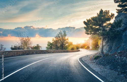 Mountain road. Landscape with rocks, sunny sky with clouds and beautiful asphalt road in the evening in summer. Vintage toning. Travel background. Highway in mountains. Transportation