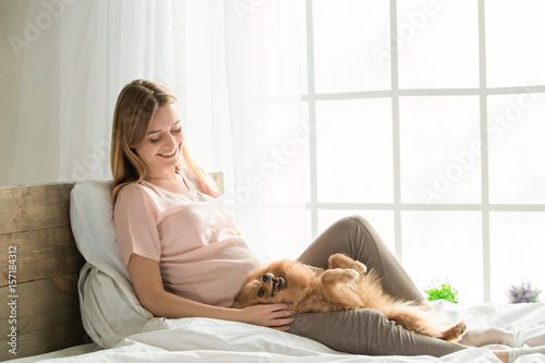 Young preganant woman expecting a baby relaxing on bed indoors photo