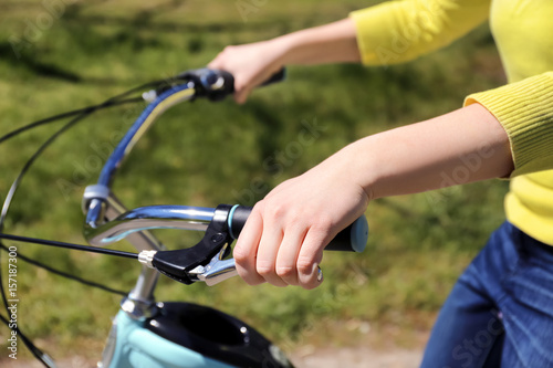 Young woman pressing bicycle brake lever on blurred background
