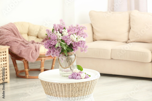 Glass vase with beautiful lilac flowers on table