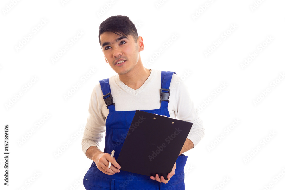 Young man in blue overall holding pen and folder Young man in blue overall holding pen and folder