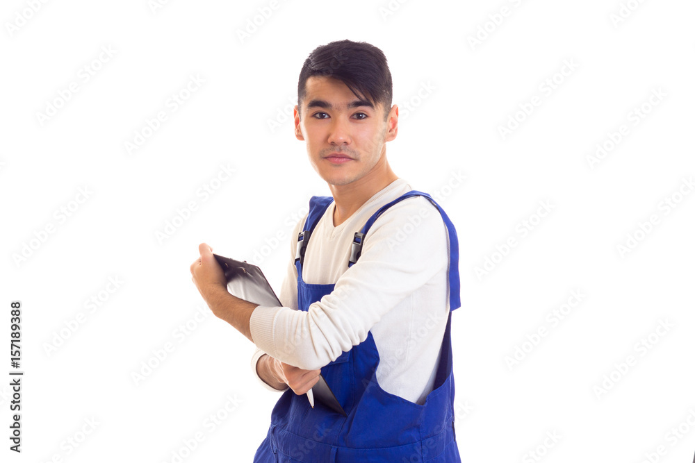 Young man in blue overall holding pen and folder Young man in blue overall holding pen and folder