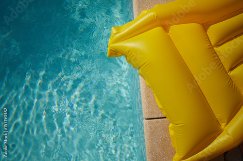 Valokuva An inflatable yellow air mattress swimming in a shiny blue swimming pool
