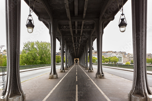 Metal columns and abutments of '' Bir Hakeim '' bridge. People walks and make jogging under the bridge in Paris.The bridge is one of the most famous and historic landmark