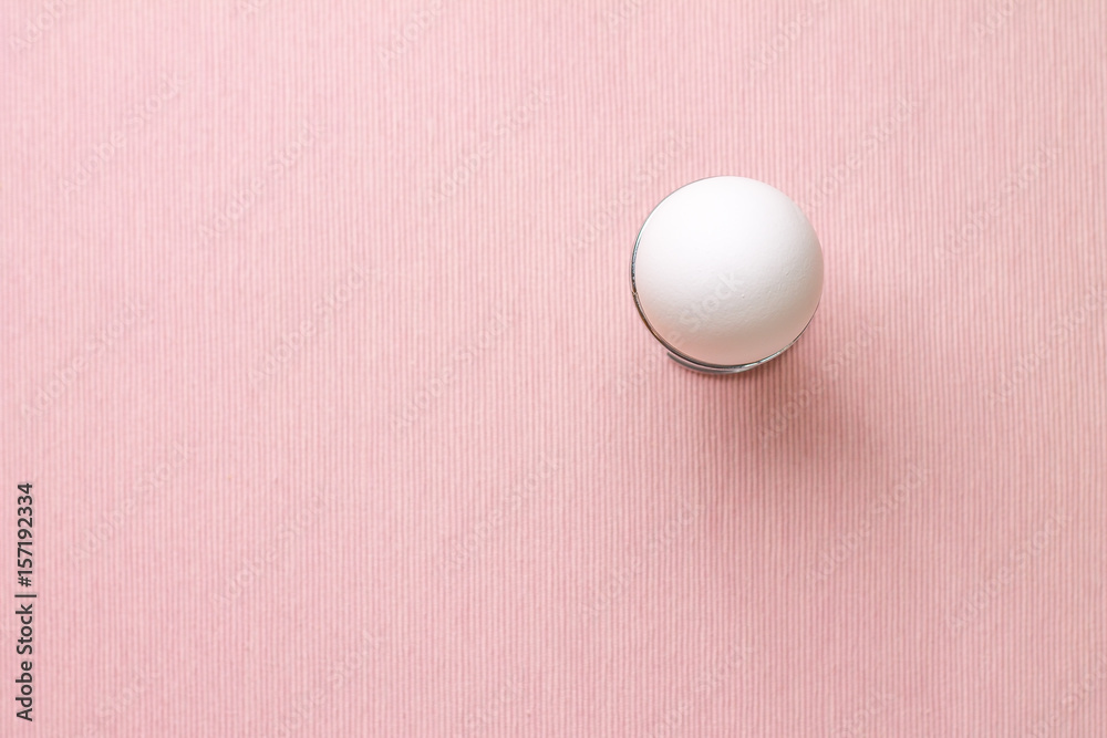 Top view of white egg in egg cup on pink Top view of white egg in egg cup on pink