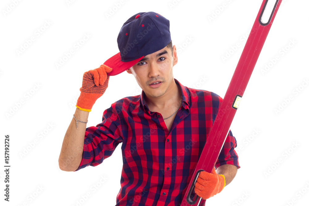 Young man in gloves and snapback holding level Young man in gloves and snapback holding level