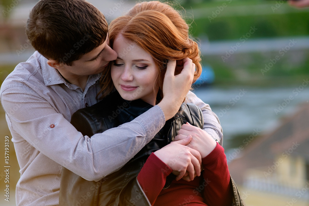Redhead pretty girl in hugs of handsome brunette man, romantic moment ...