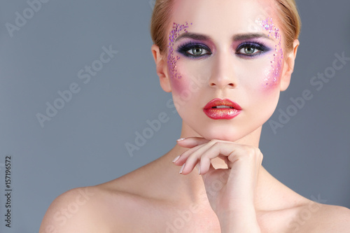 Beautiful young woman with creative makeup on color background