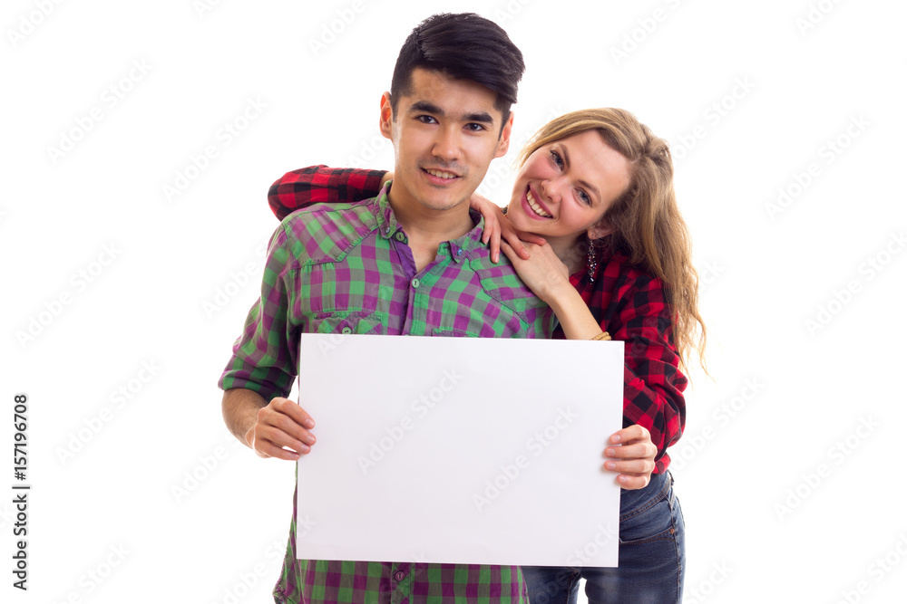 Young couple in plaid shirts holding placard Young couple in plaid shirts holding placard