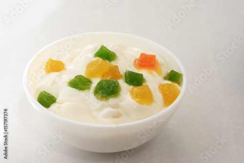  Yogurt with slices of fruit and candied fruits on a white background