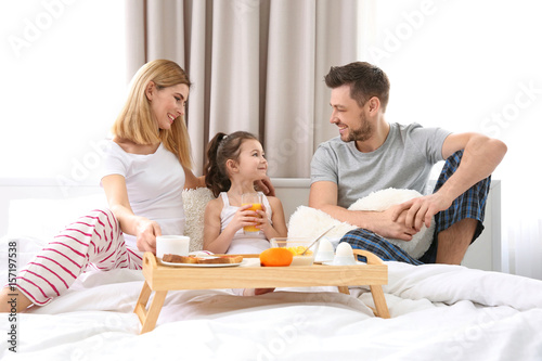 Happy family sitting on bed...