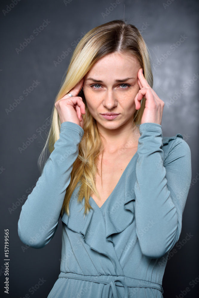 Blonde girl holding hands near his head because of headache Blonde girl holding hands near his head because of headache
