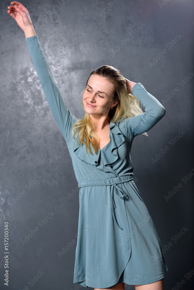 Blond girl dancing on a gray wall background Blond girl dancing on a gray wall background