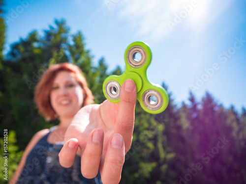 Fotografie Young woman holding a green fidget spinner