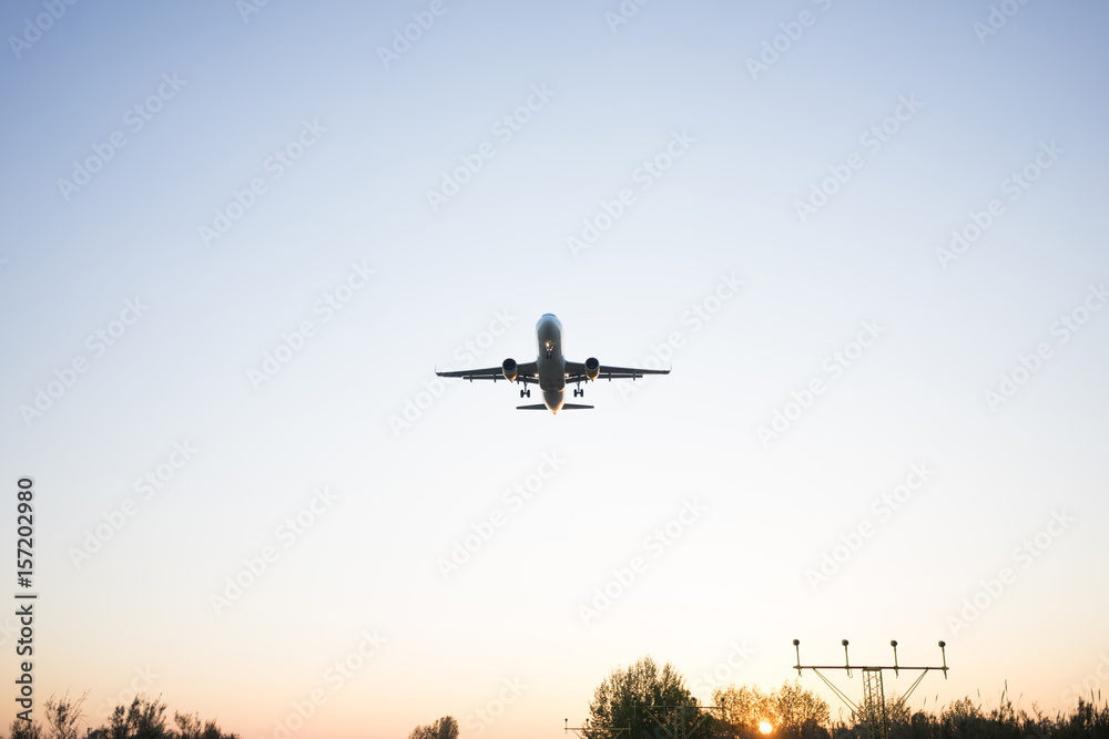 Silhouette of airplane which lands above fields on soft sunrise in blue clear sky close to aeroport. Silhouette of airplane which lands above fields on soft sunrise in blue clear sky close to aeroport.
