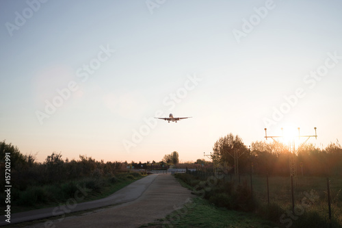 Airplane sits down above fields on sunrise close to aeroport.