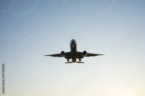 Silhouette of airplane sitting down above fields on sunrise in blue clear sky close to aeroport.