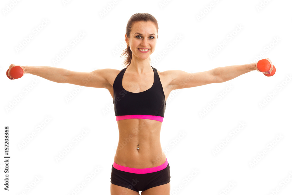 young beautiful girl smiling keeps hands at the sides with dumbbells and looking forward young beautiful girl smiling keeps hands at the sides with dumbbells and looking forward