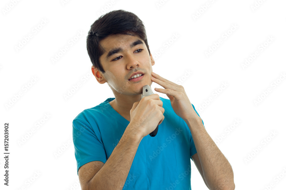 cute young guy with black hair looks ahead and carefully shaves his beard cute young guy with black hair looks ahead and carefully shaves his beard