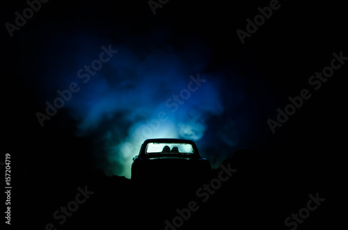 silhouette of car with couple inside on dark background with lights and smoke. Romantic scene. Love concept