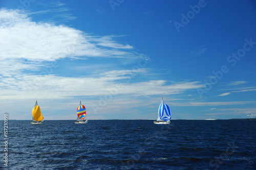 Yachting race. Sailing regatta. Three small yachts with colorful spinnakers in the sea on sunny windy day