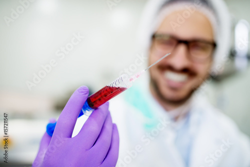 Close up of a doctors hand holding syringe with blood. Analyzing blood in the laboratory.